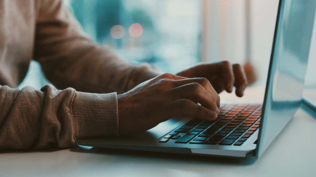 close up of a person's hands typing on a laptop